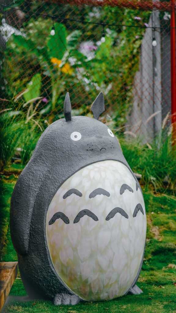我愛龍貓 a statue of a totoro sitting in the grass