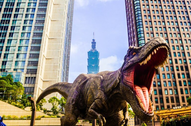 日本的恐龍博物館 dinosaur with open mouth beside buildings still selective focus photography of