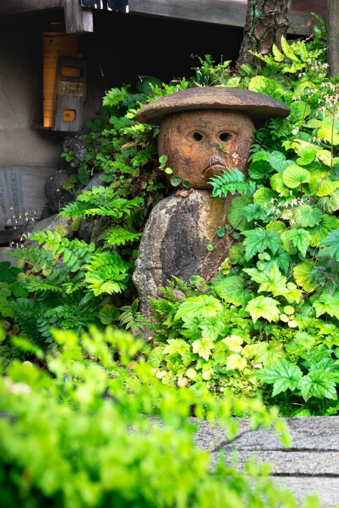 日本傳說中的河童 a statue of a bear in a bush with a hat on