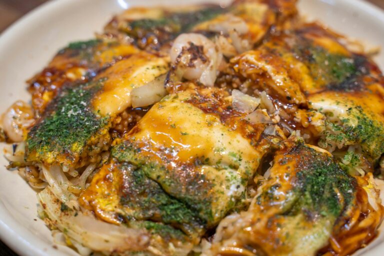 大阪燒與大阪 a white plate topped with broccoli covered in cheese